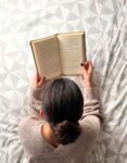 une femme de dos lit un livre